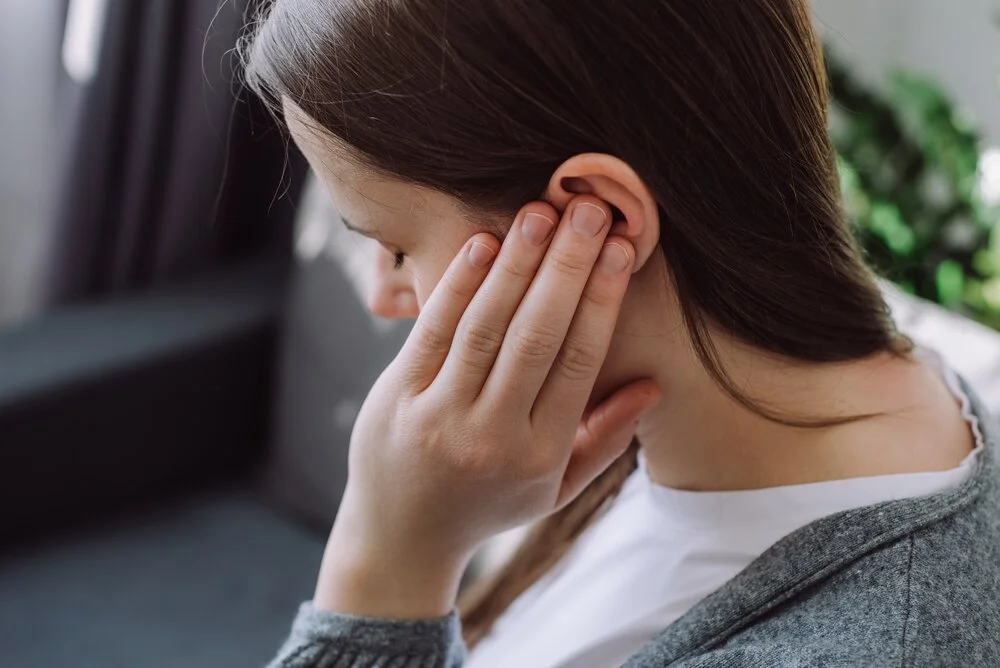 Close up up of sick young caucasian female touching ear